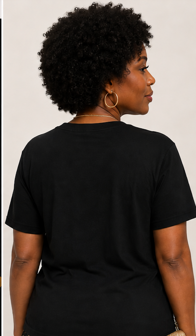 A woman with curly black hair is shown from the back wearing a plain black short-sleeve t-shirt and gold hoop earrings against a light beige background.