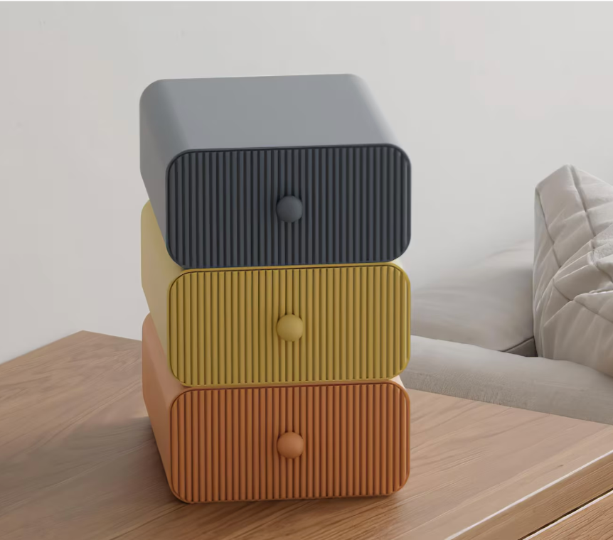 Stack of three textured drawers in gray, yellow, and brown on a wooden surface.